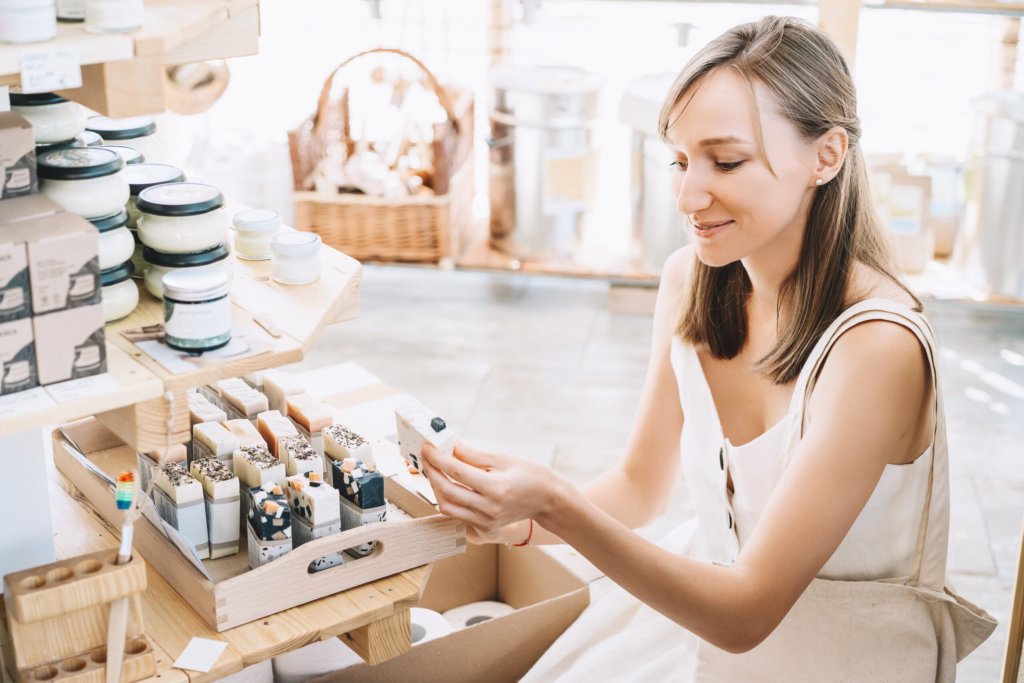 Woman with cotton bag buying personal hygiene items in zero waste shop. Eco Organic Cosmetics. Girl choose toiletries products in plastic free store. Minimalist lifestyle. Shopping at local businesses